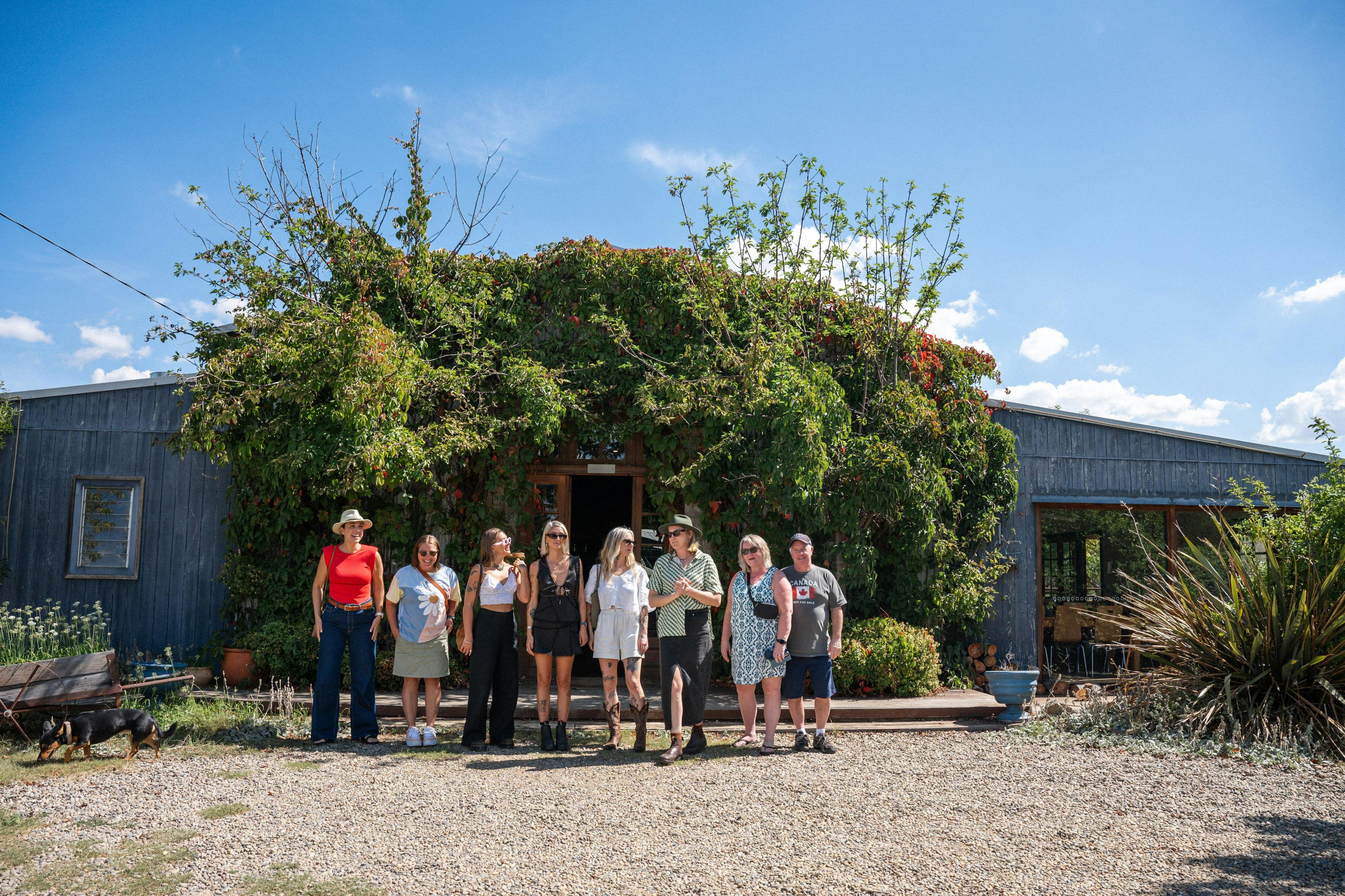 ダルゲティ醸造所のセラードアの前にいるツアー客のグループ、澄み切った青い空と緑豊かな庭園