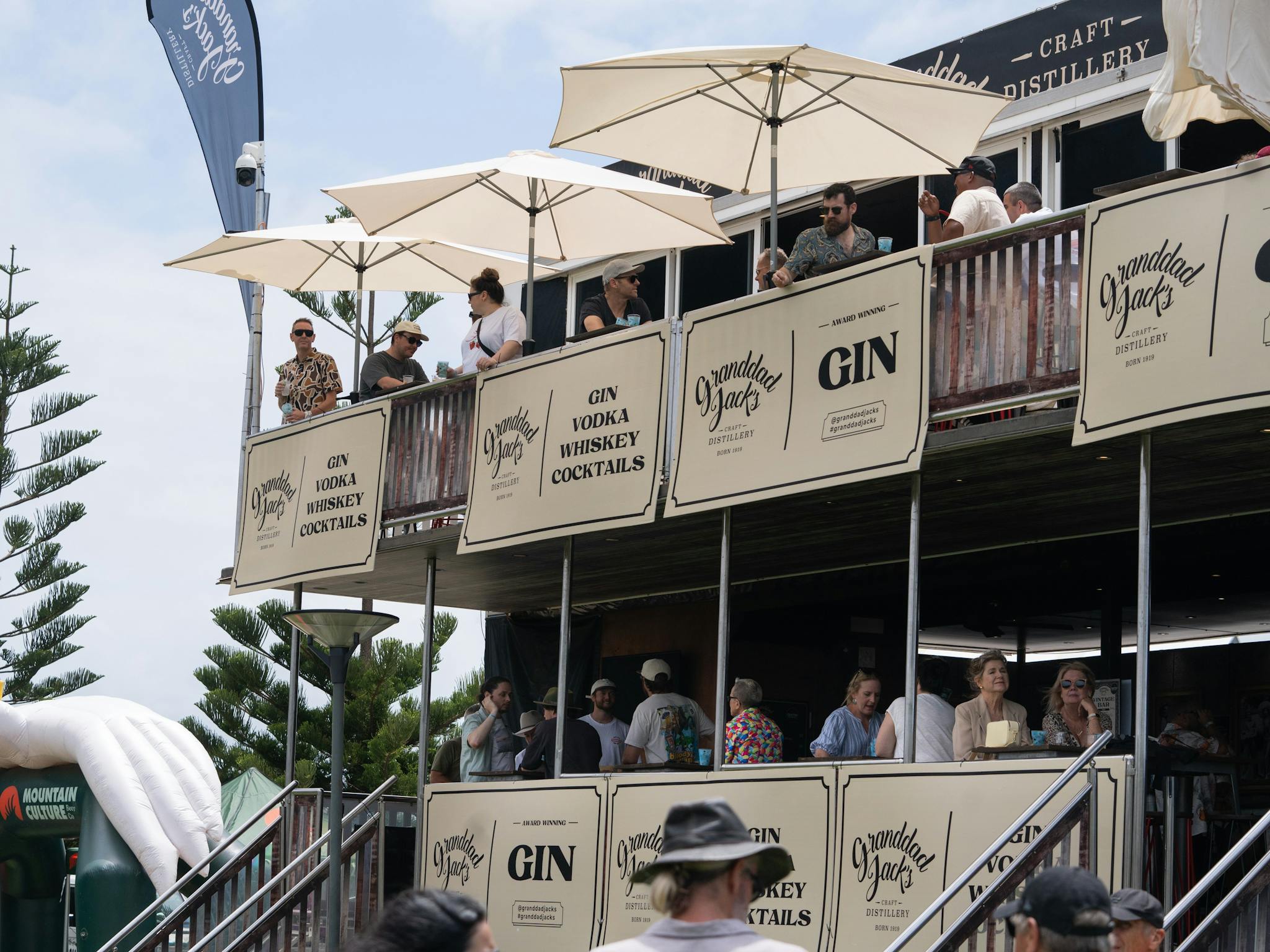A two storey bar with umbrellas with people sitting drinking gin in the sun