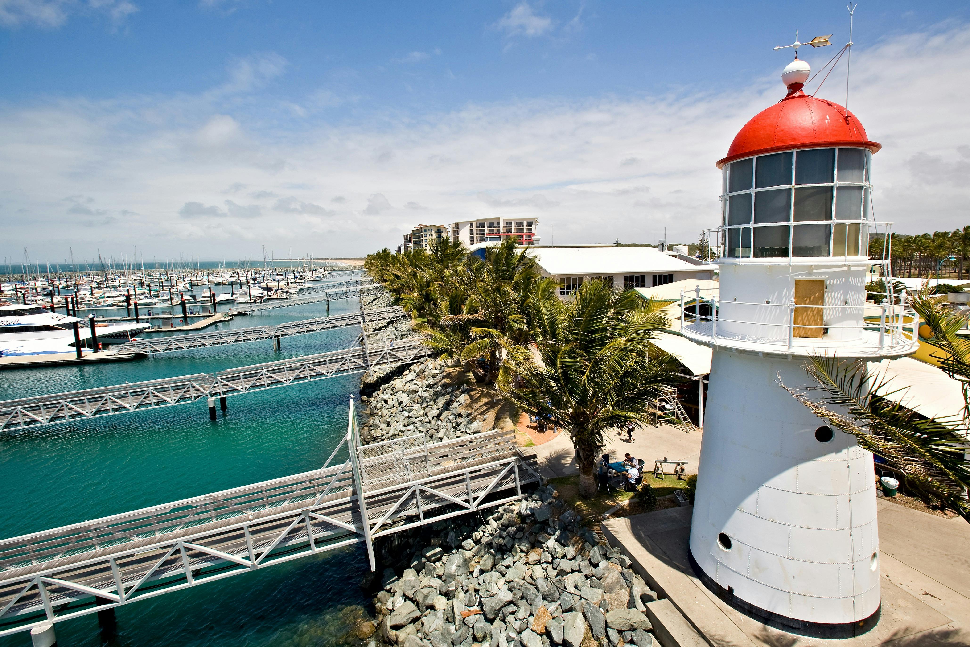 Aerial shot of the Pine Islet lighthouse at the Mackay Marina, boats, jettys, rockwall and water.