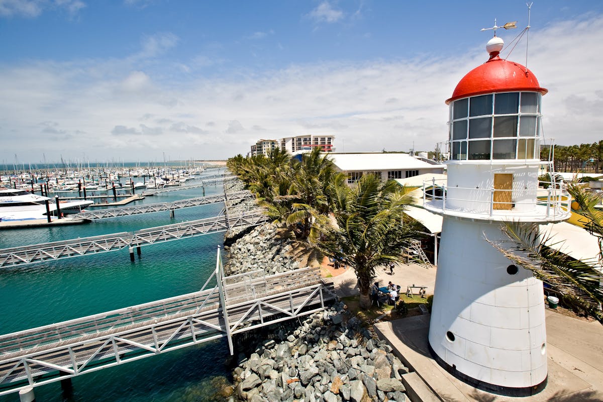 Aerial shot of the Pine Islet lighthouse at the Mackay Marina, boats, jettys, rockwall and water.