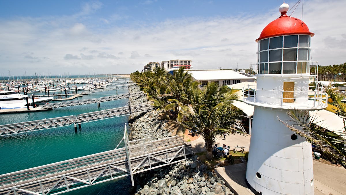 Aerial shot of the Pine Islet lighthouse at the Mackay Marina, boats, jettys, rockwall and water.