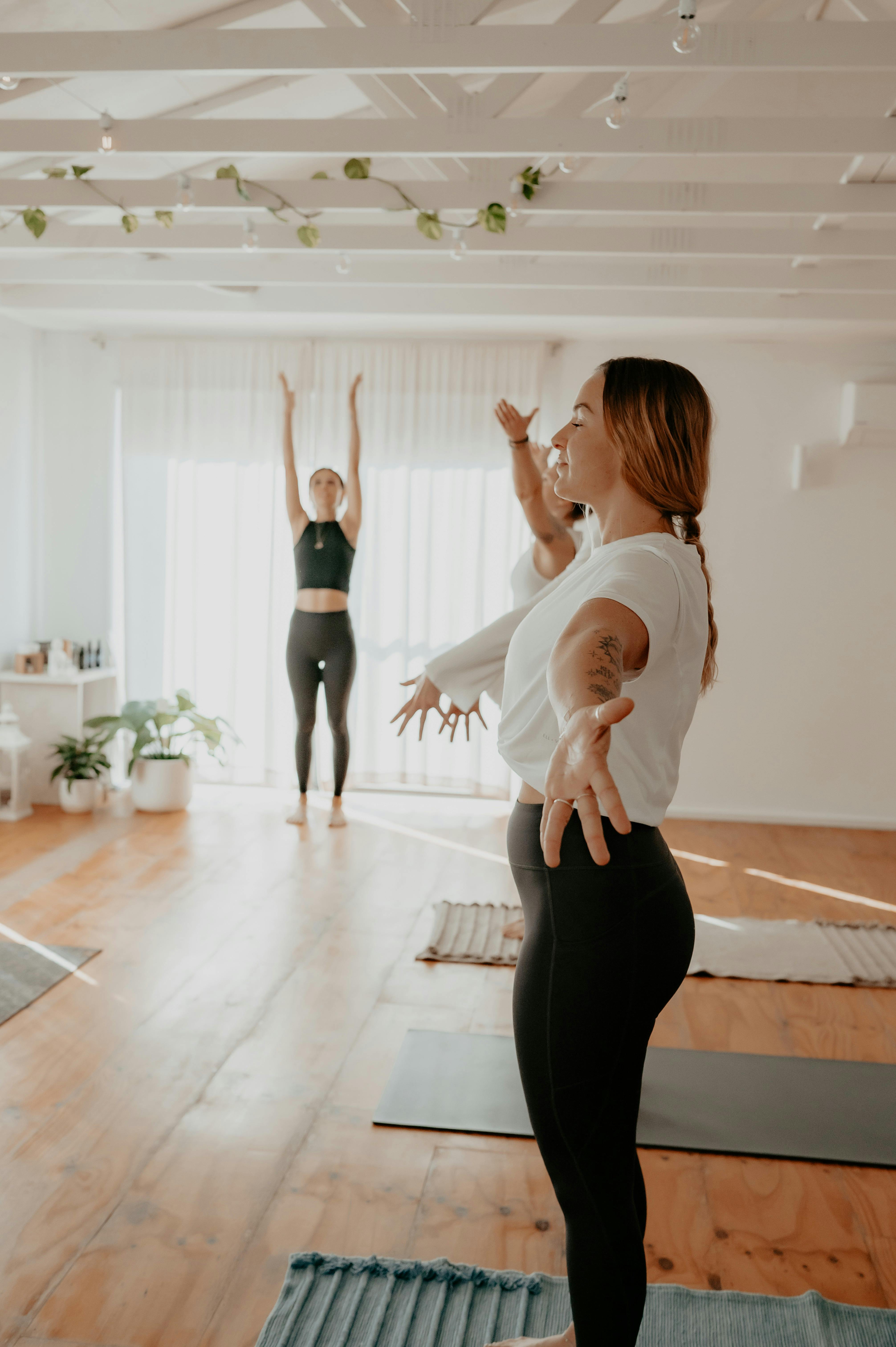 3 yoga students salute to the sun with yoga teacher