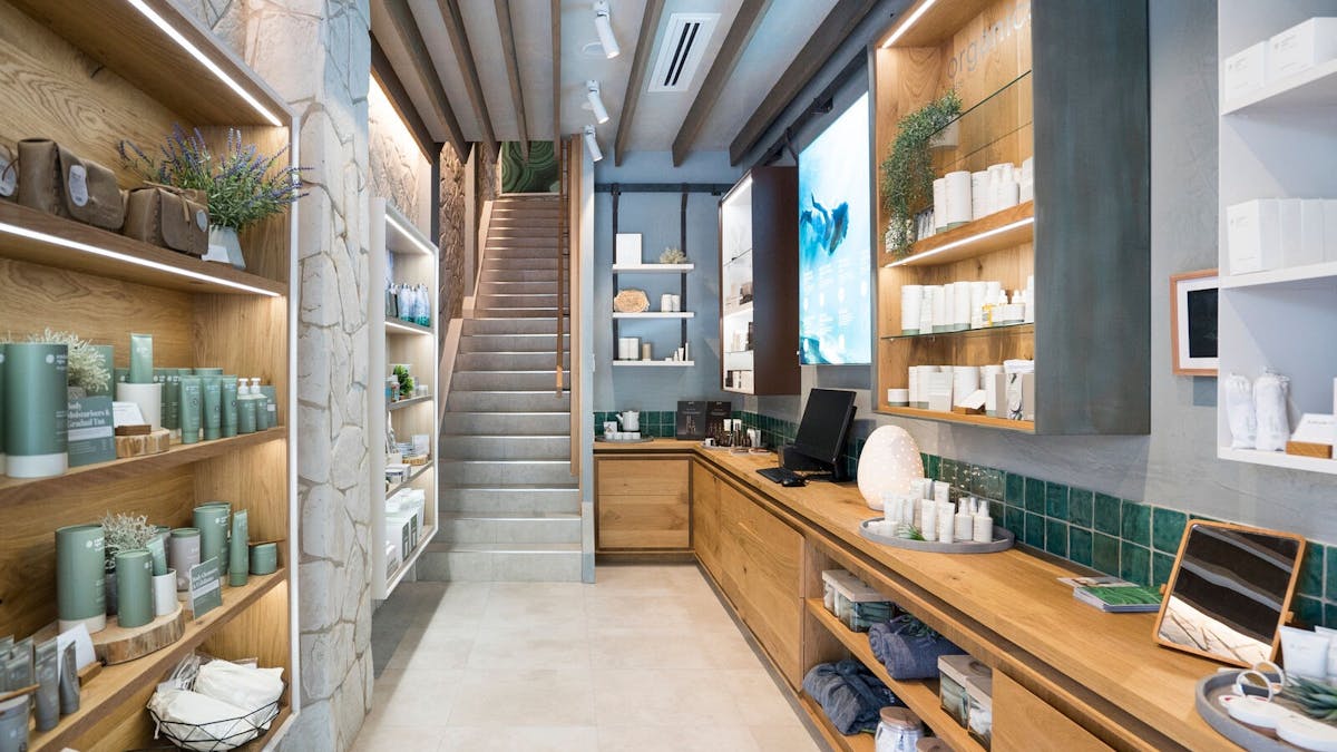Spa store with skincare and wellness products on shelving, staircase at end of photograph