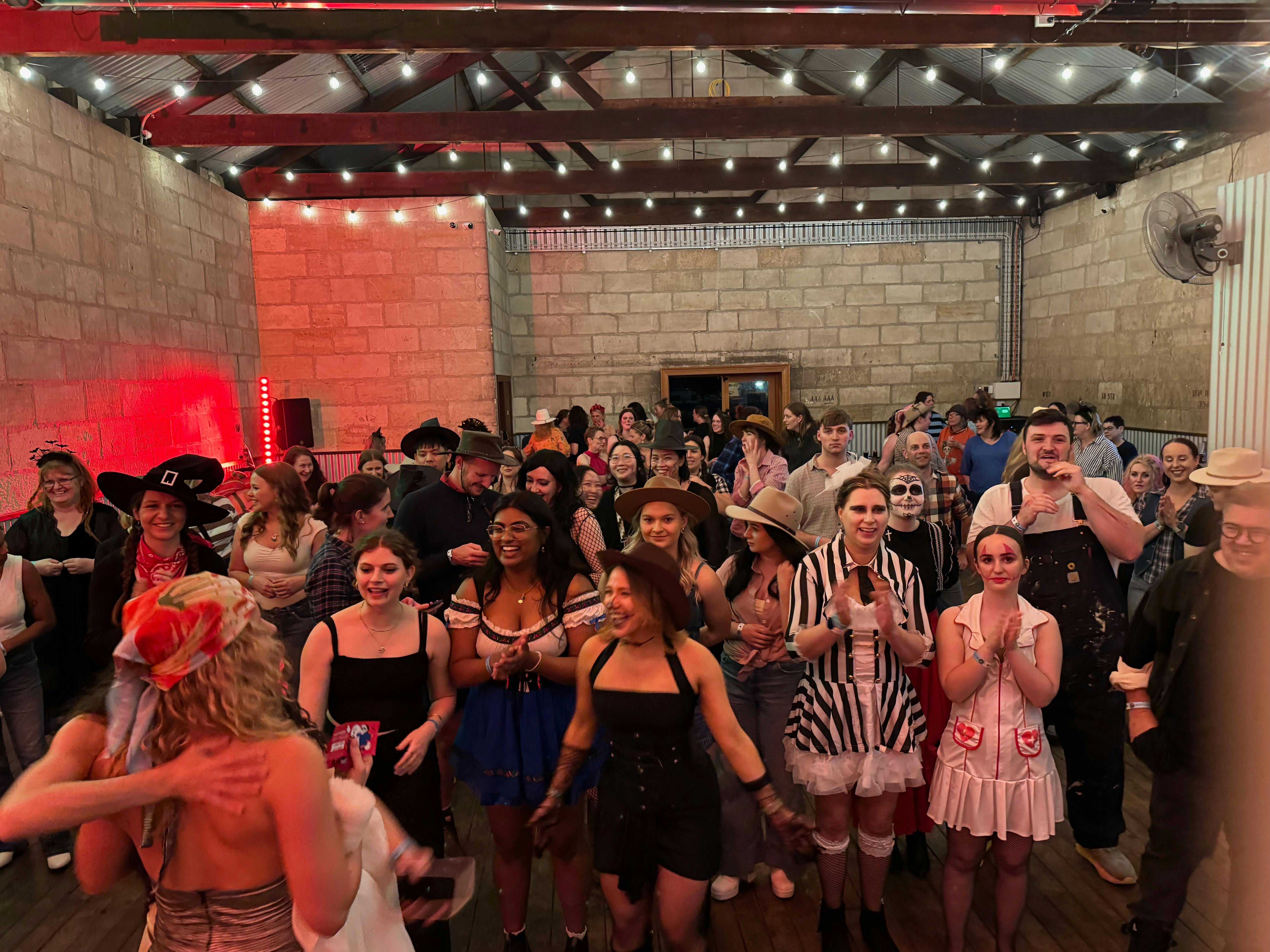 Large group of people dressed in halloween costumes dancing and laughing