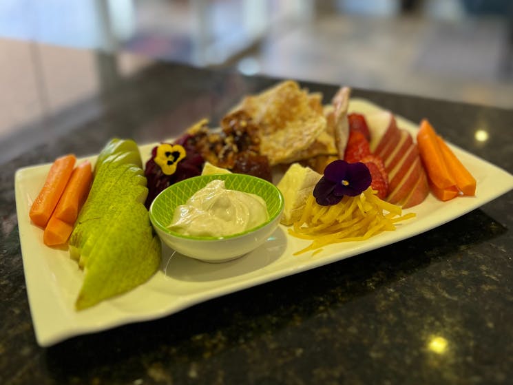 A colorful platter of fruits, vegetables, cheese and other treats.