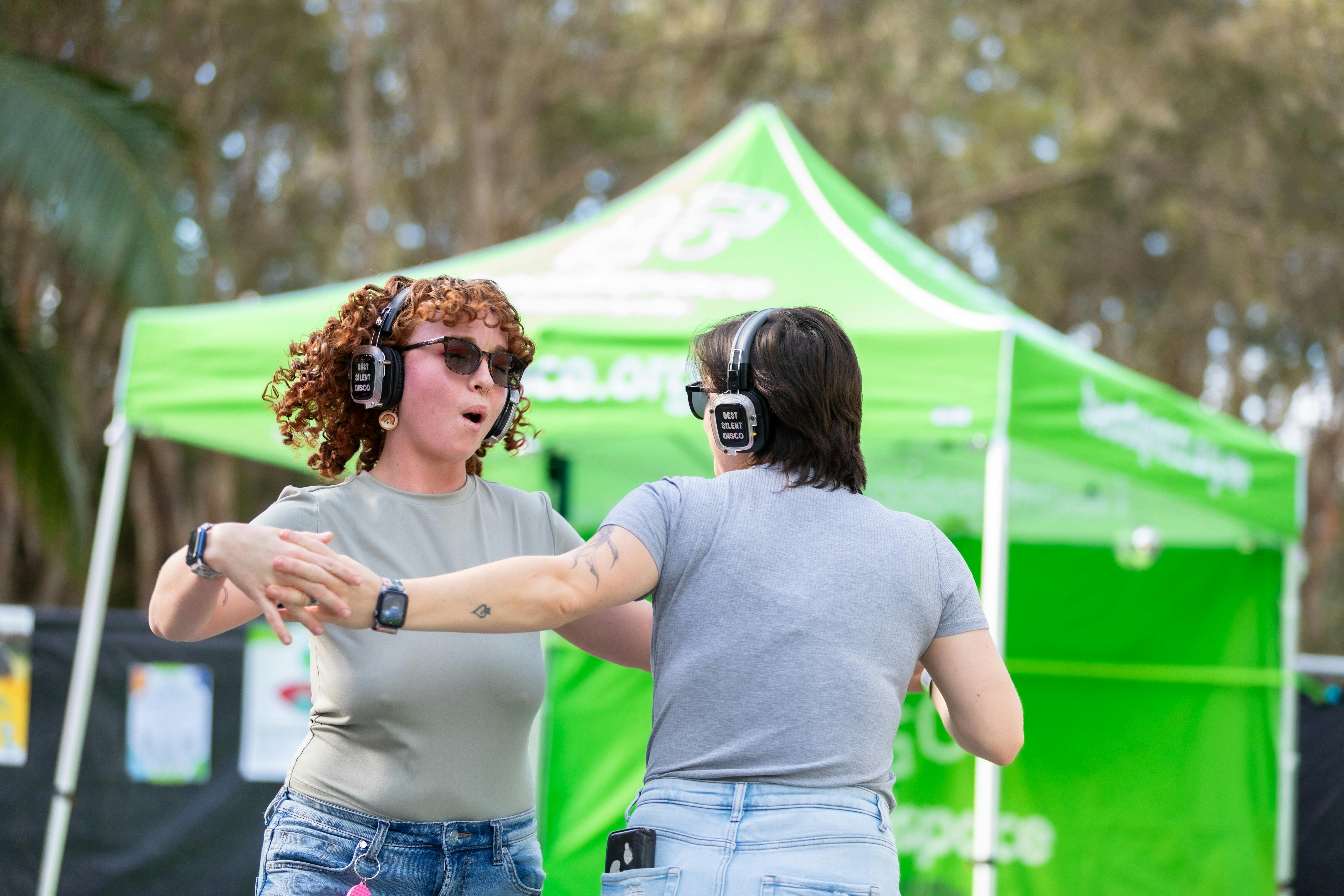 Two people dance together at the silent disco at Moreton Bay PrideFest, wearing wireless headphones