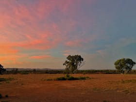 Dirt grounds next to the hotel with rainbow sunset colours of pink, orange and blue