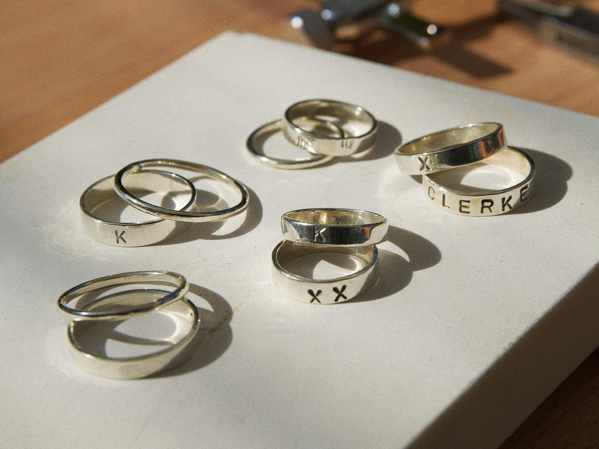 Handmade silver rings with unique engravings, displayed on a white board in natural light. Handmade silver rings with unique engravings, displayed on a white board in natural light.