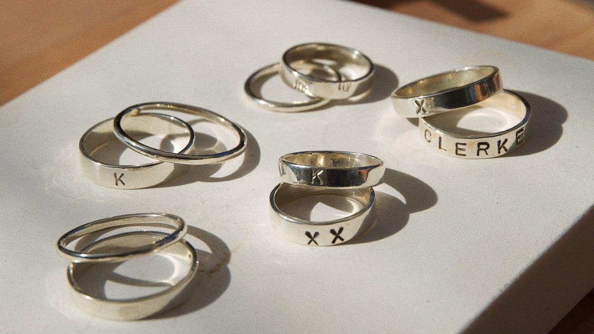 Handmade silver rings with unique engravings, displayed on a white board in natural light.