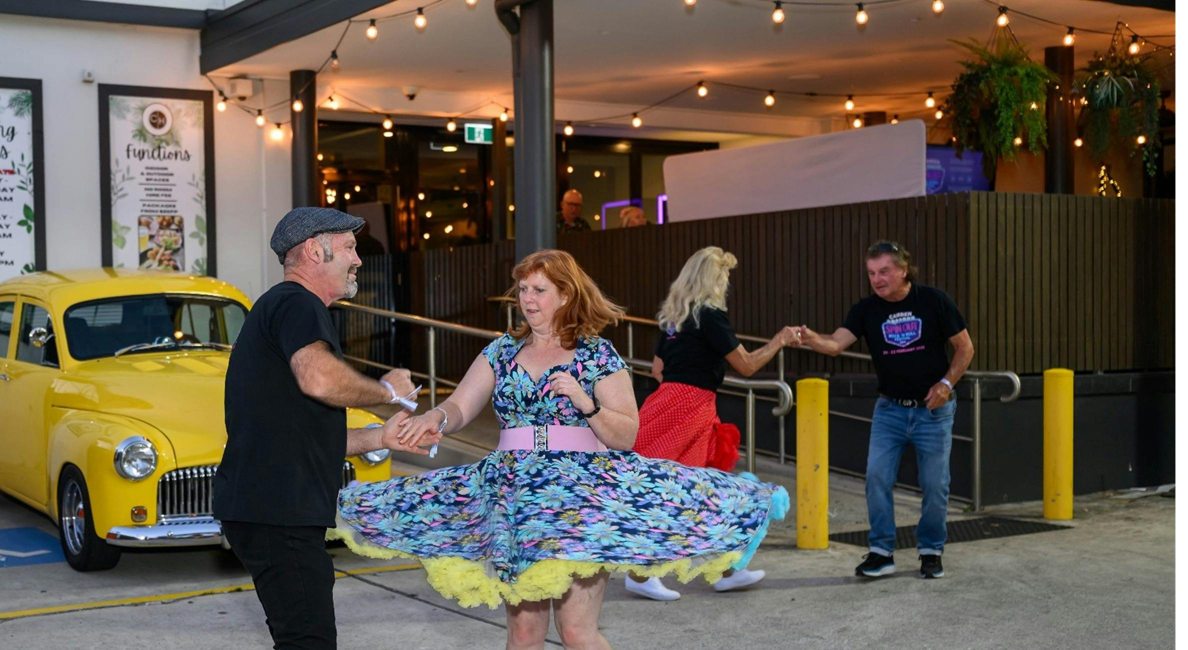 People  dancing with a vintage car for a back drop