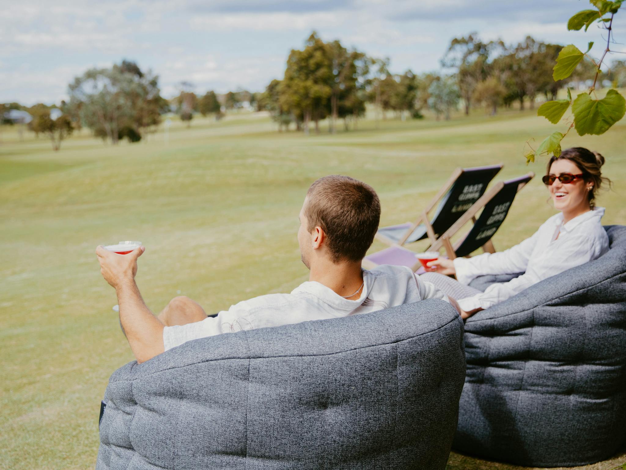 Couple enjoying drinks on outdoor lounges overlooking Golf course