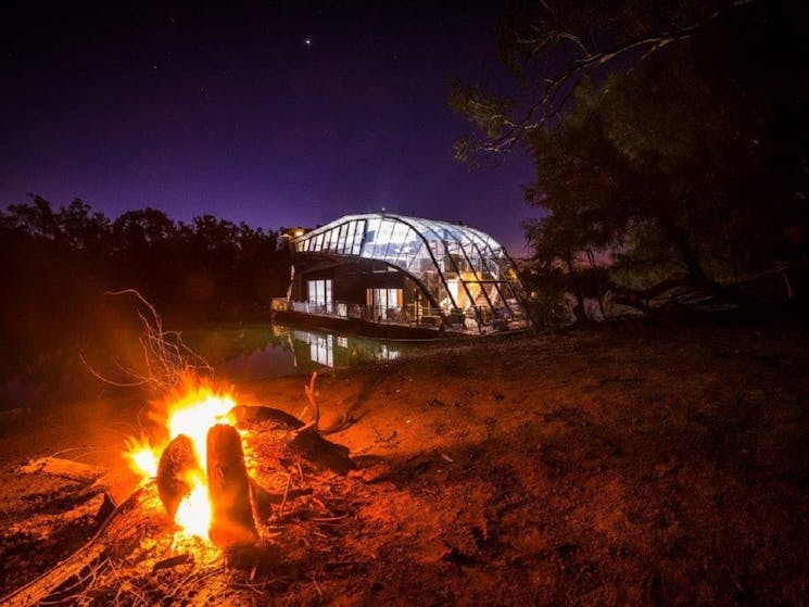 a night shot of houseboat with a fire pit in front