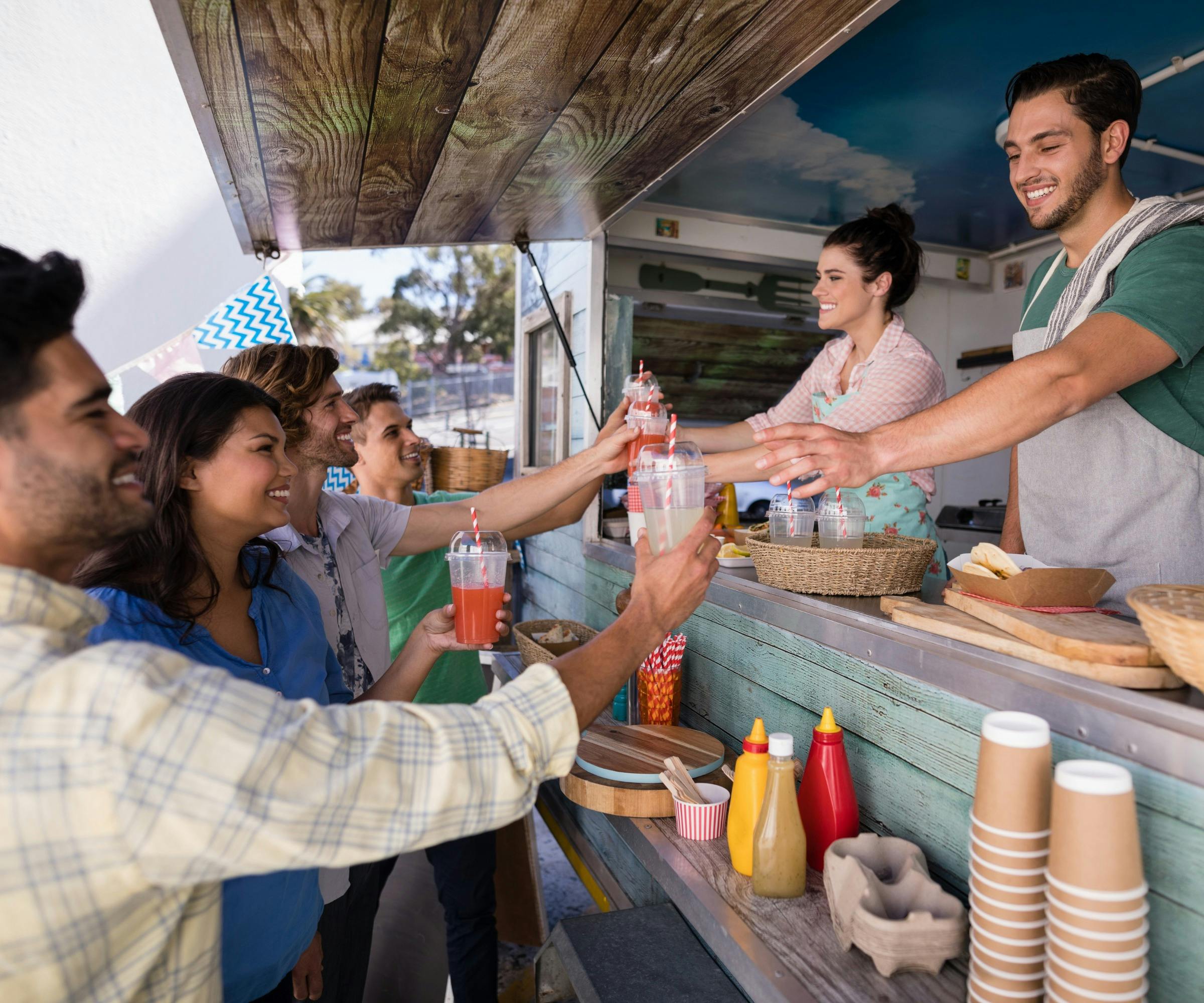 A group of people buying drinks from a food stall.