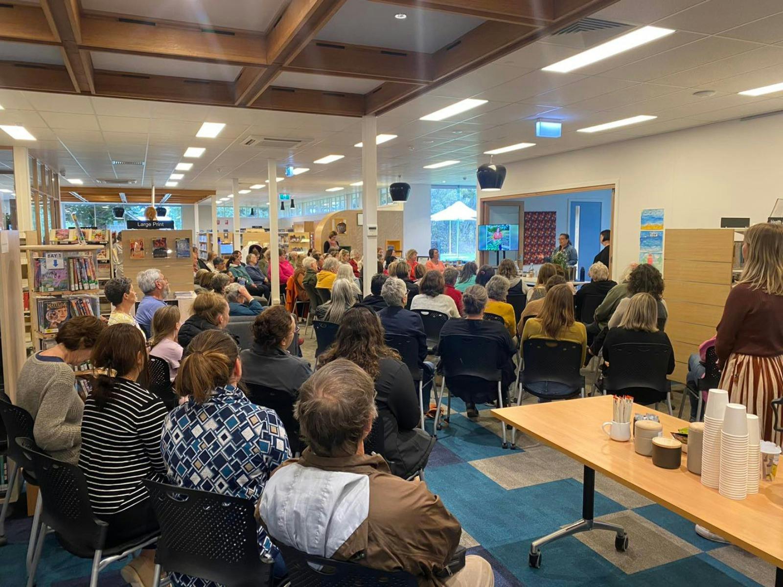 Group of people sitting down in a library engaging in talk event