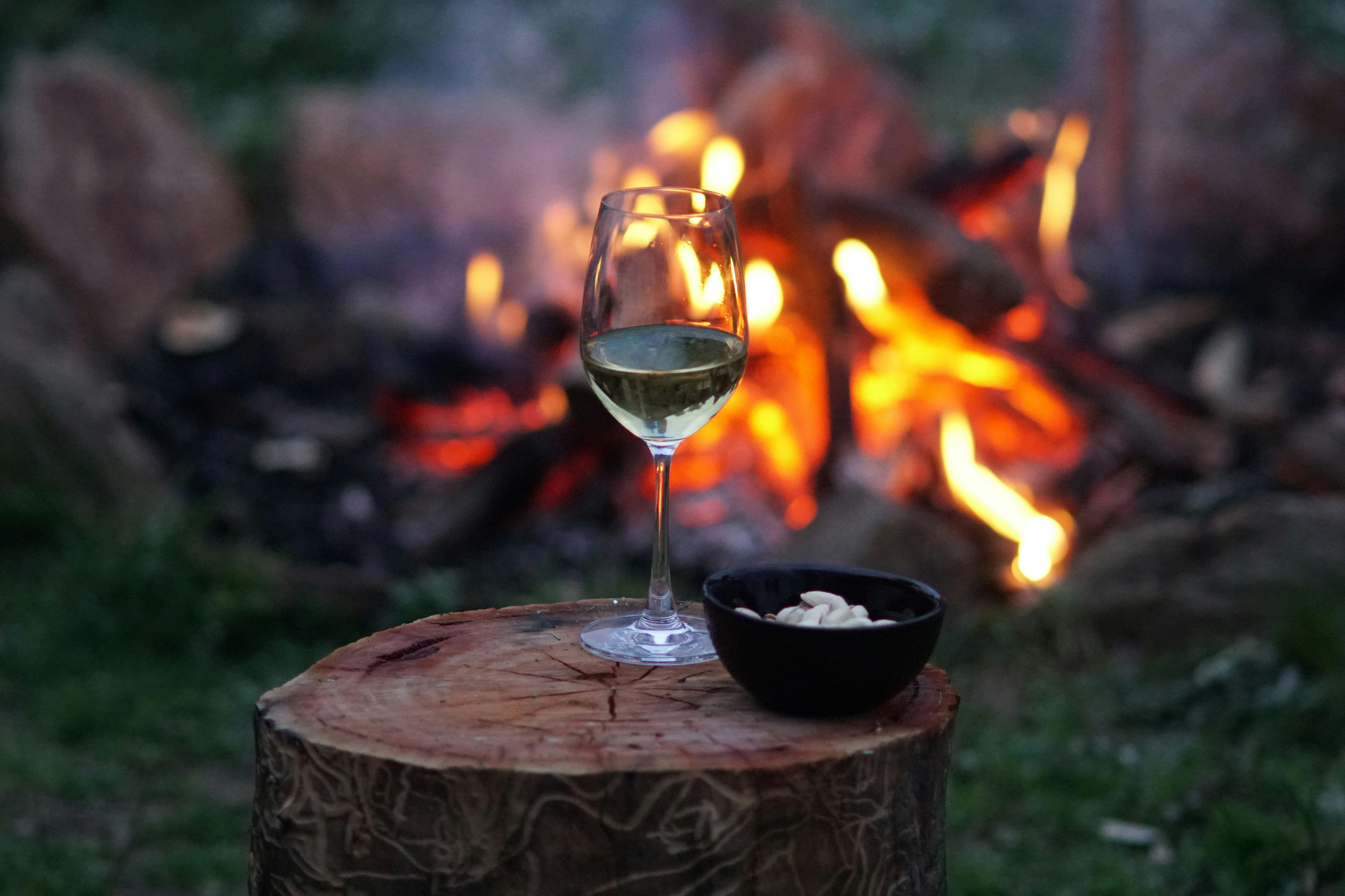 ワイングラスとボウルに入ったナッツが置かれた屋外の焚き火台
