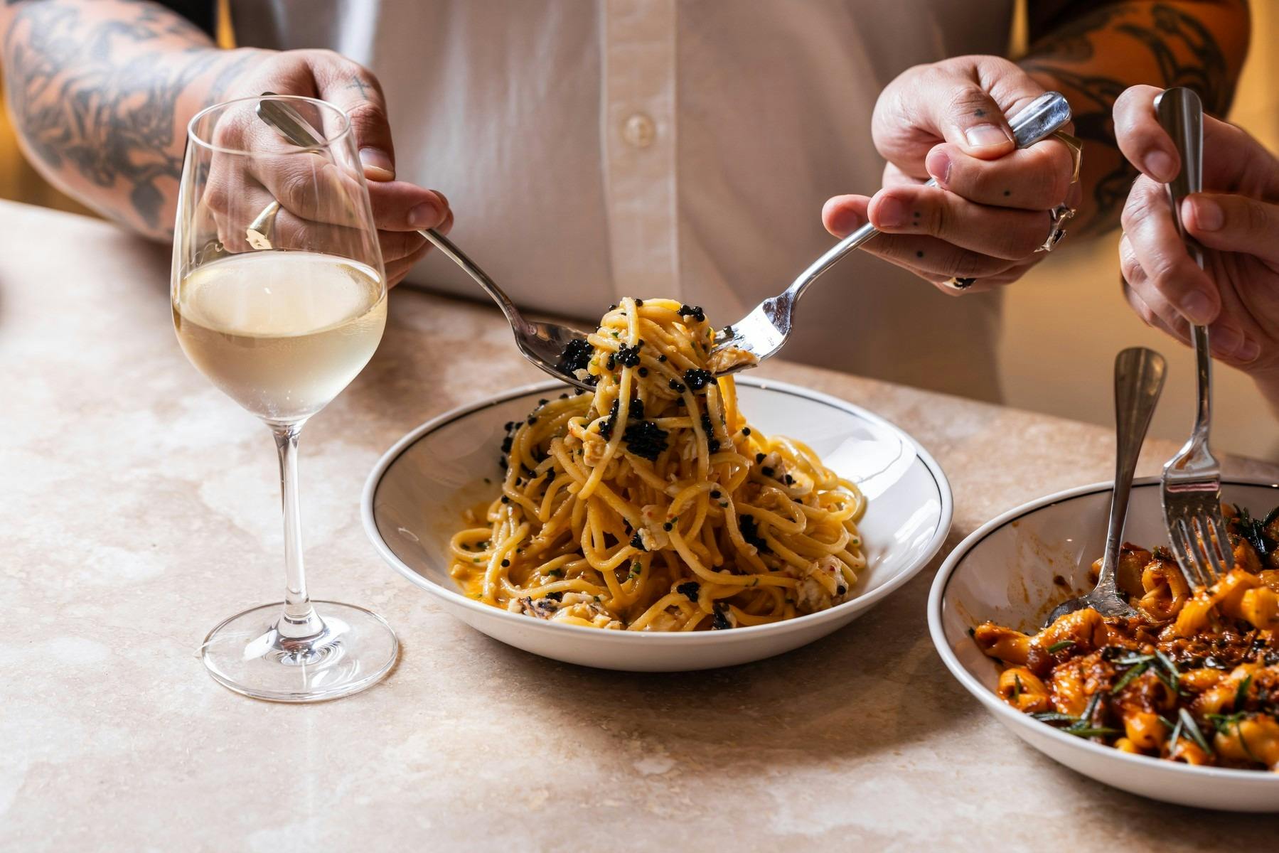 A bowl of pasta and glass of white wine
