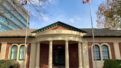 Image of 1920's red brick building with cream portico, green arched windows, and two flag poles.