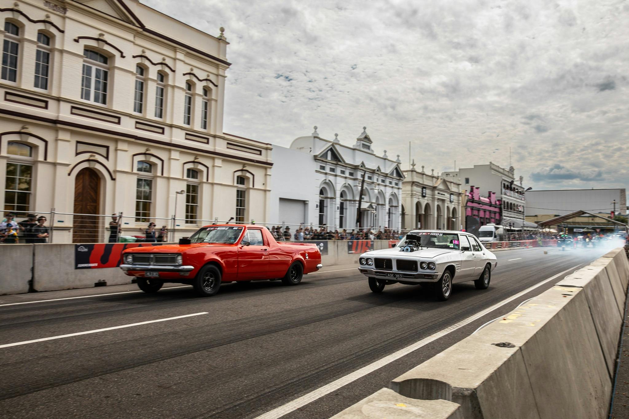 Two cars racing side by side on a closed city street during Rockynats.