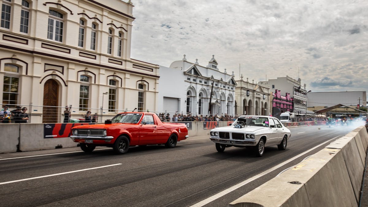 Two cars racing side by side on a closed city street during Rockynats.
