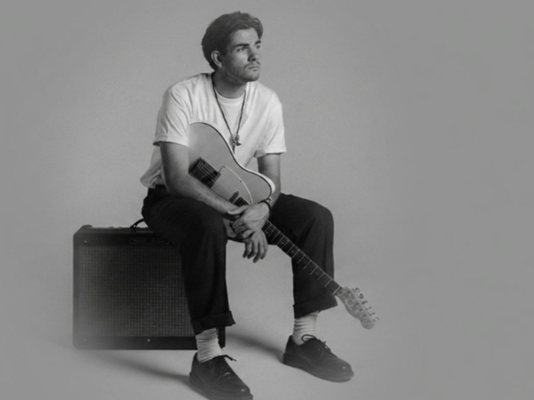 Flynn Gurry sitting on an amp holding his guitar