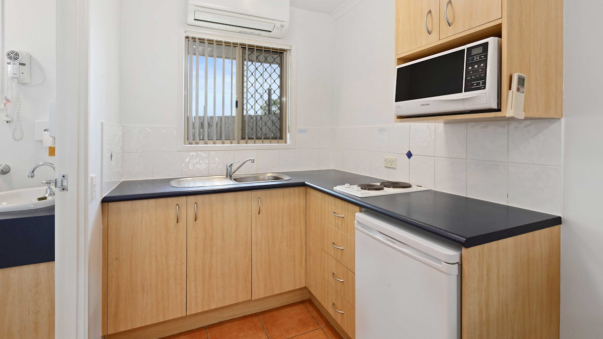 Small kitchenette with mini fridge, sink, microwave and stove top