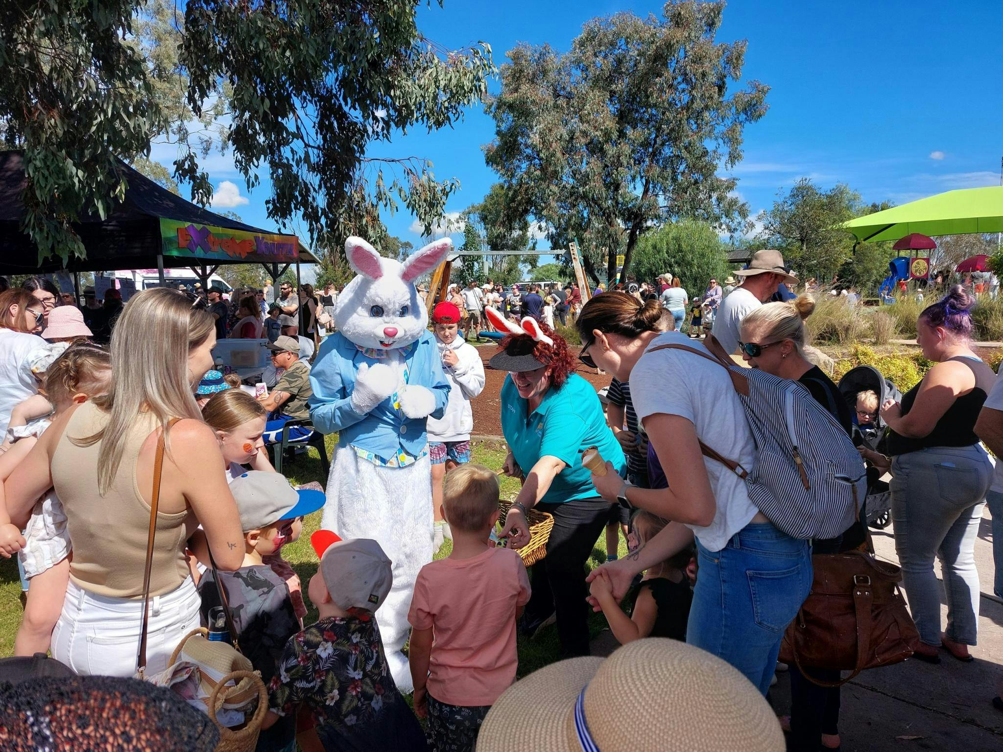 Entertainer in white Easter Bunny costume encircled by children and parents/carers