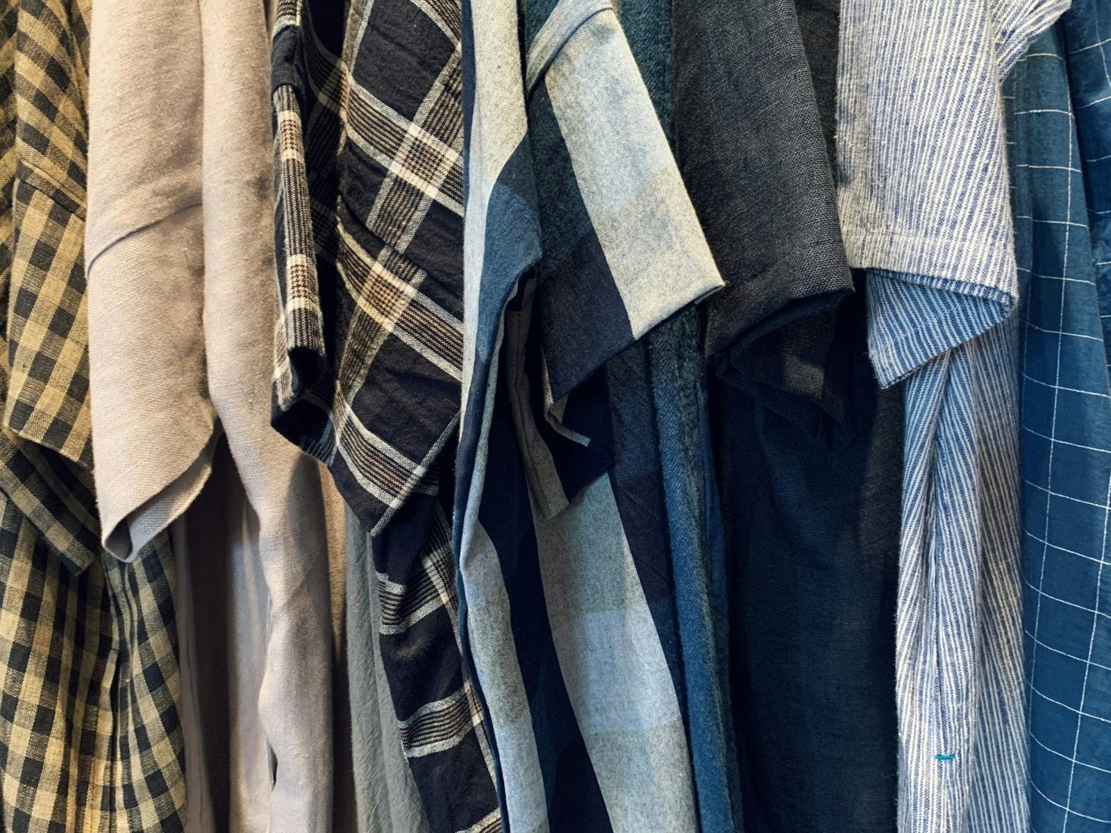 Different colours and textures of linen garments hang from the racks at the maker