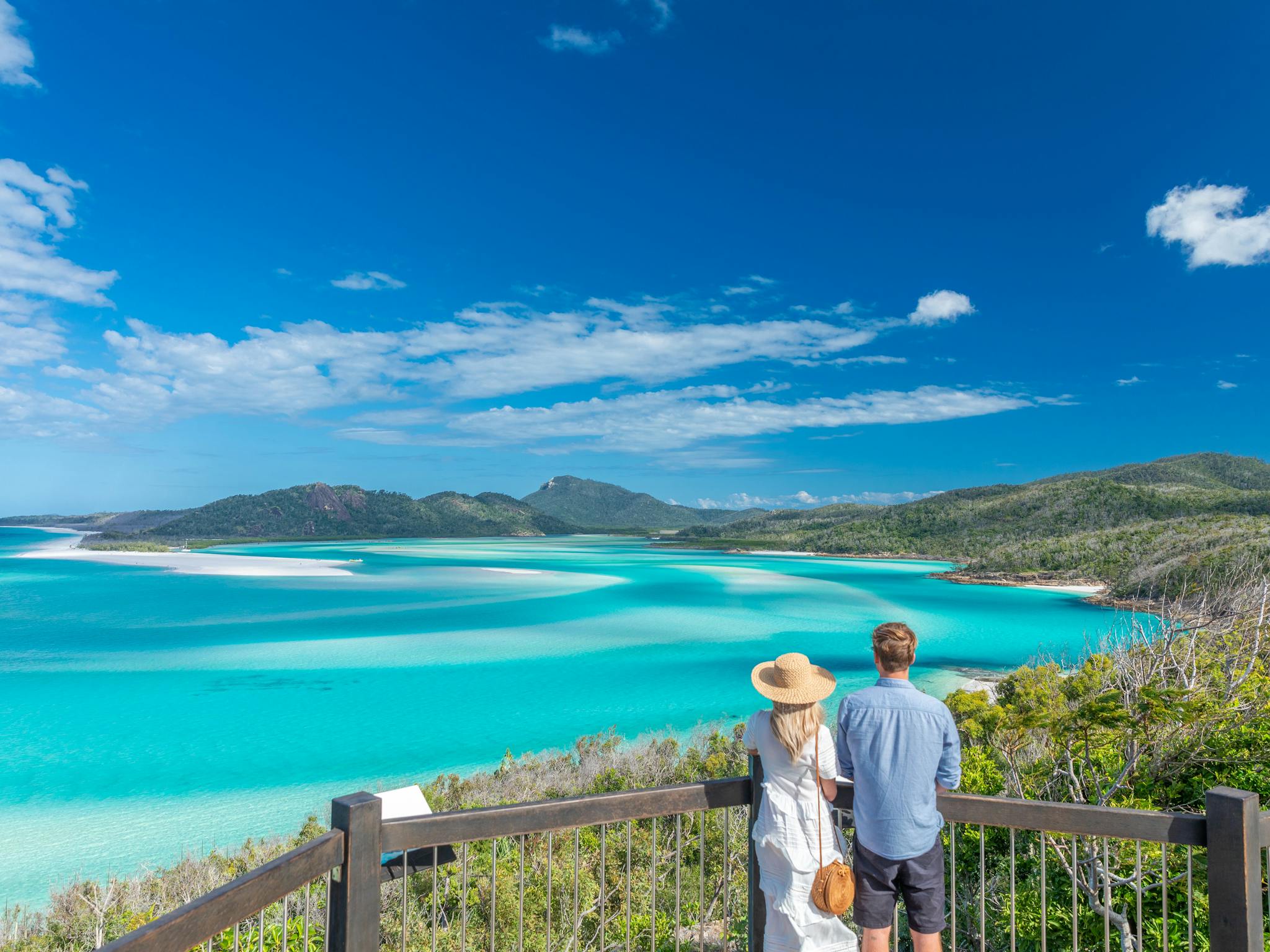 A woman and a man looking over the swirling sands and turquoise waters of the inlet from a lookout A woman and a man looking over the swirling sands and turquoise waters of the inlet from a lookout