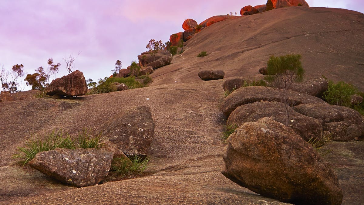Looking upward from the base of a granite pyramid. Smaller granite rocks balance on the pyramid.