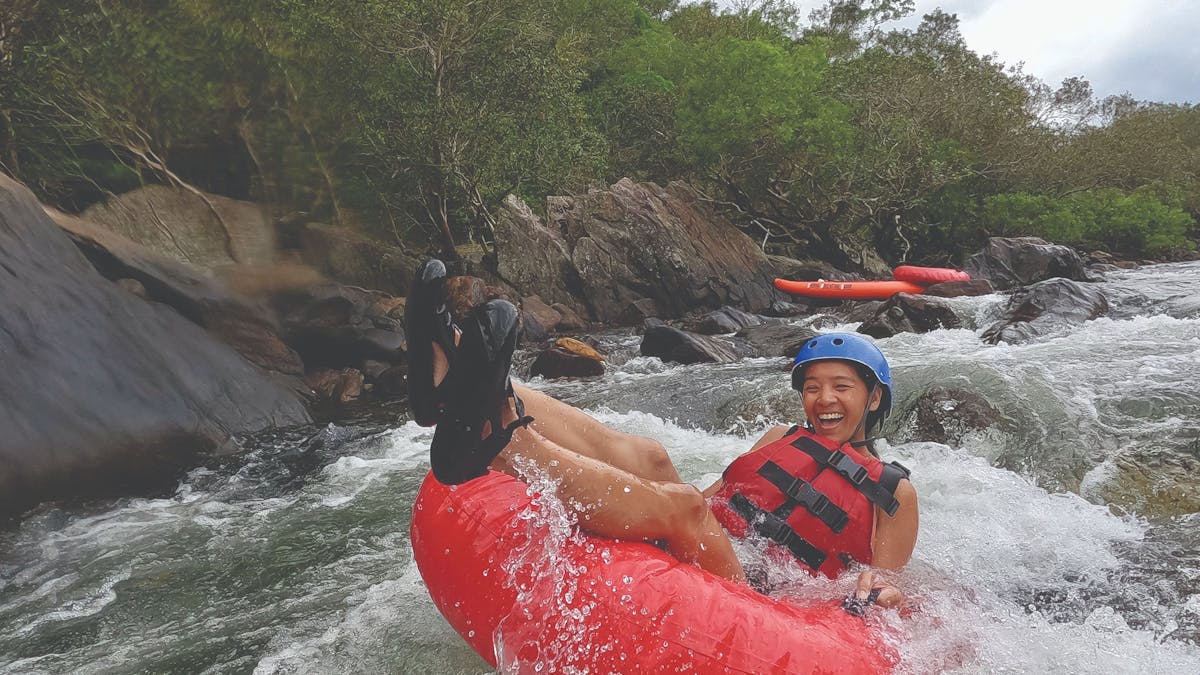 Woman tubing down rapid in safety gear in Tropical North Queensland Wooroonooran National Park Woman tubing down rapid in safety gear in Tropical North Queensland Wooroonooran National Park