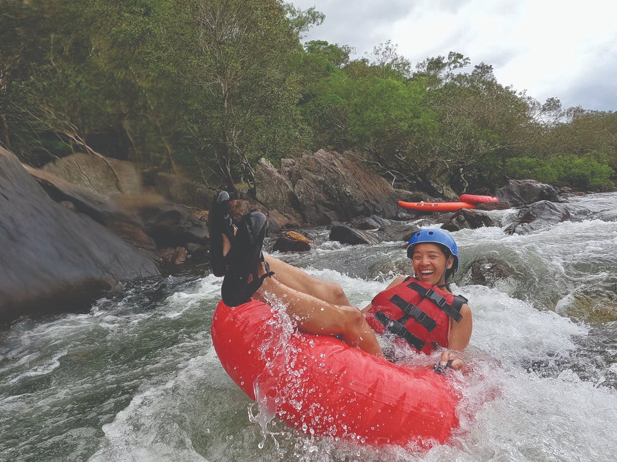 Woman tubing down rapid in safety gear in Tropical North Queensland Wooroonooran National Park