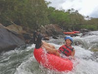 Woman tubing down rapid in safety gear in Tropical North Queensland Wooroonooran National Park