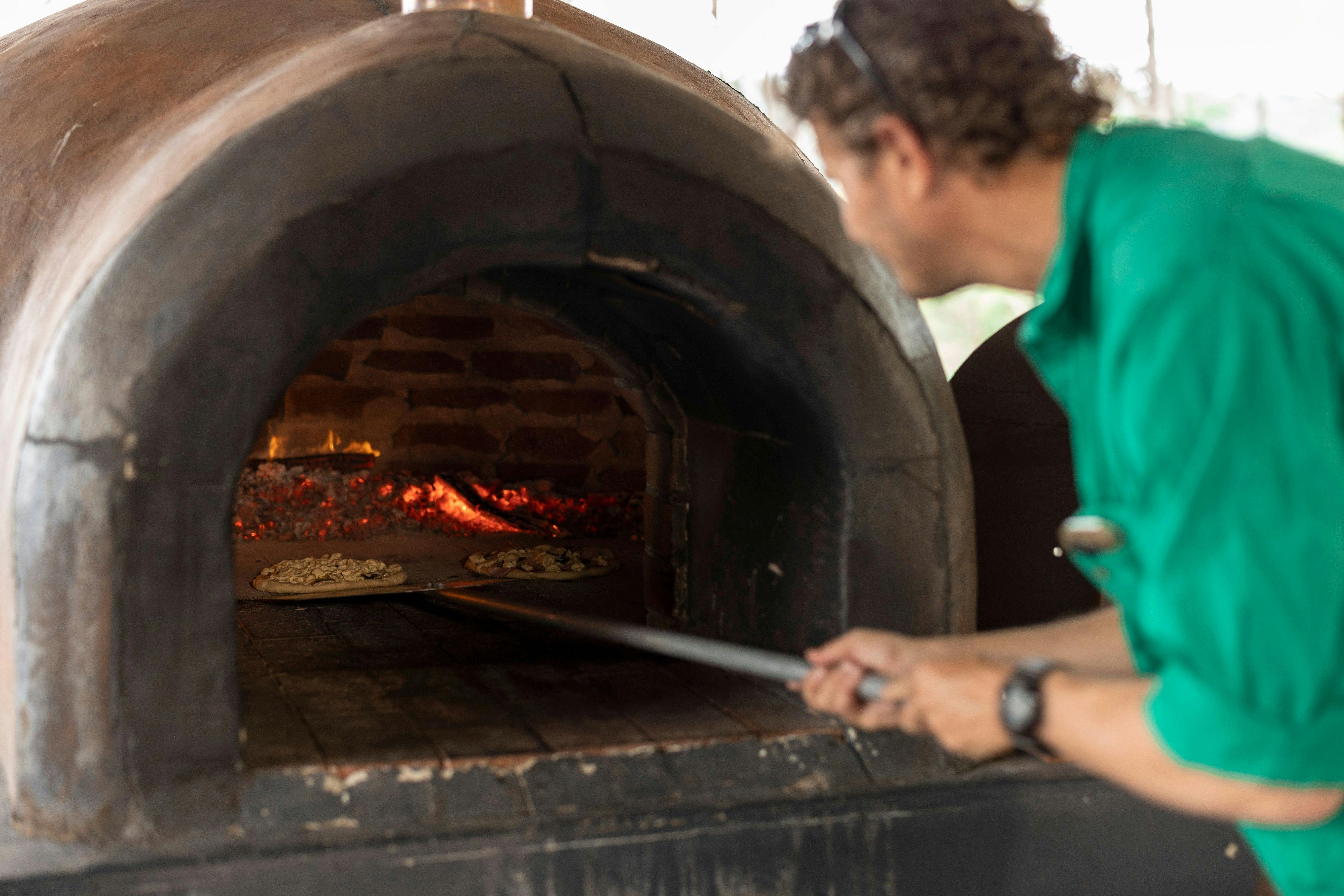 Man placing pizza in a wood fired oven