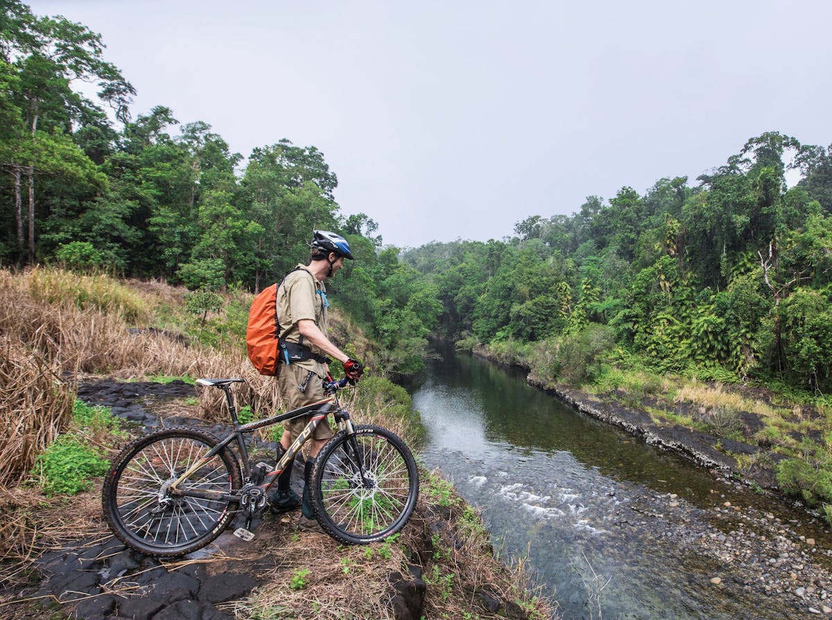 Mountain biker on high bank over Mulgrave River.