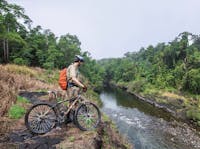 Mountain biker on high bank over Mulgrave River.