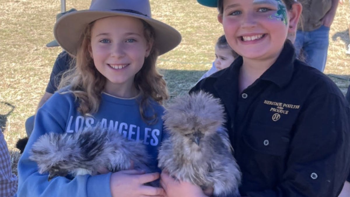 two young girls holding chickens and smiling