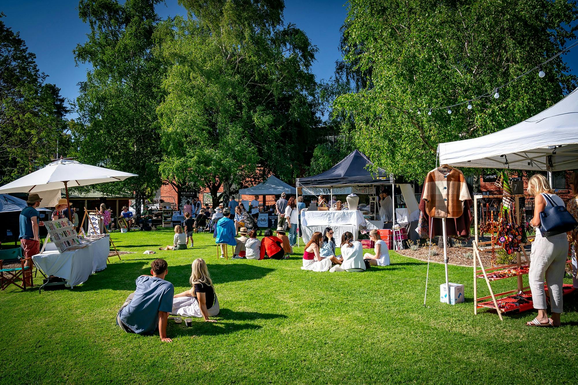 People seated and chatting near stalls at FABRIK Arts + Heritage Handmade Christmas Market