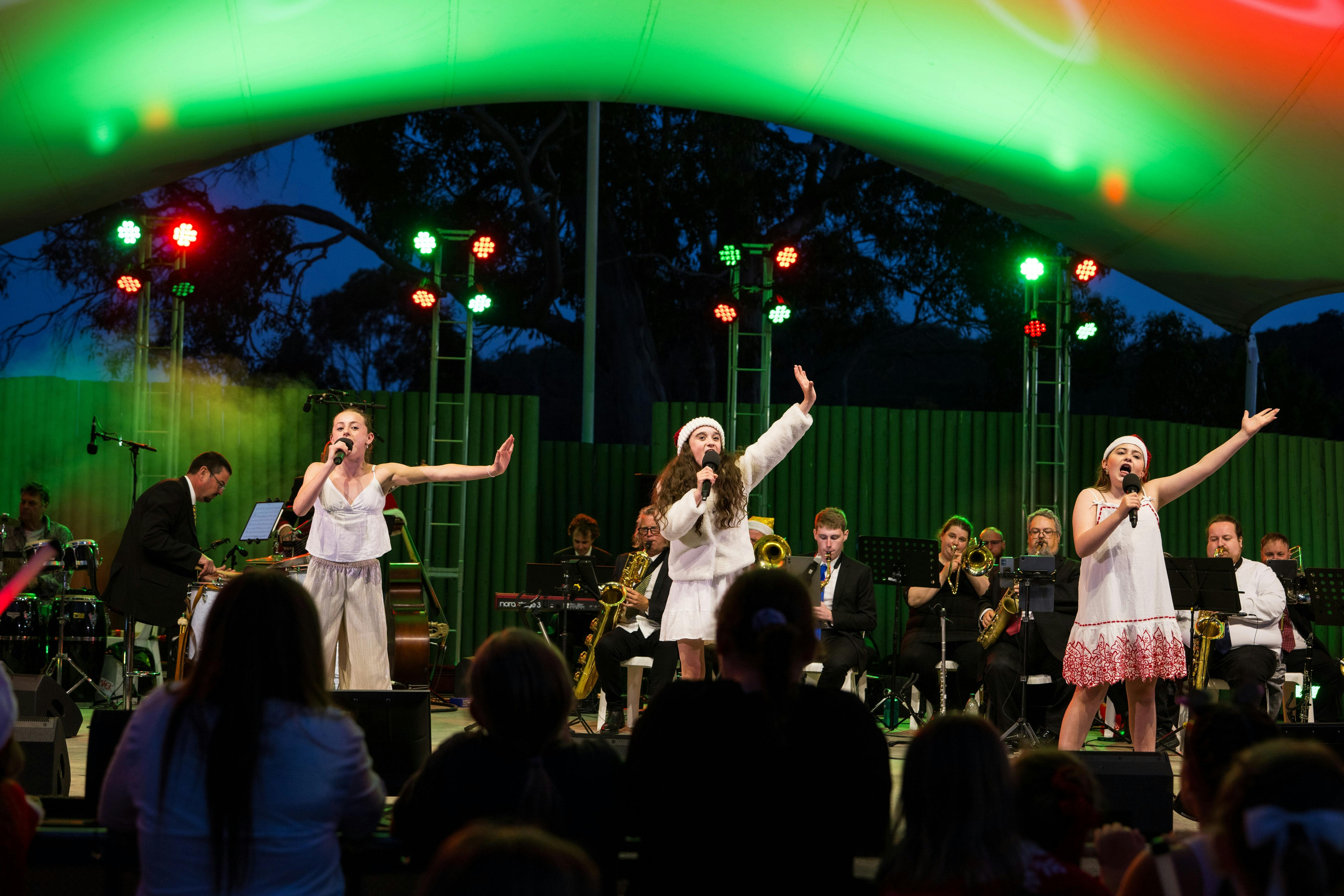 three young singers on stage at the Carols by Candlelight