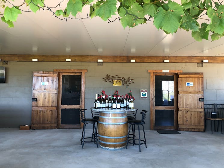 Wine barrel table with selection of wine and bar stools, outside undercover at cellar door