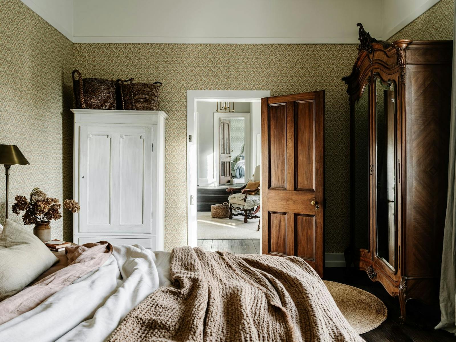 A bedroom looking through to a landing and another room, with textural decor timber furnishings.
