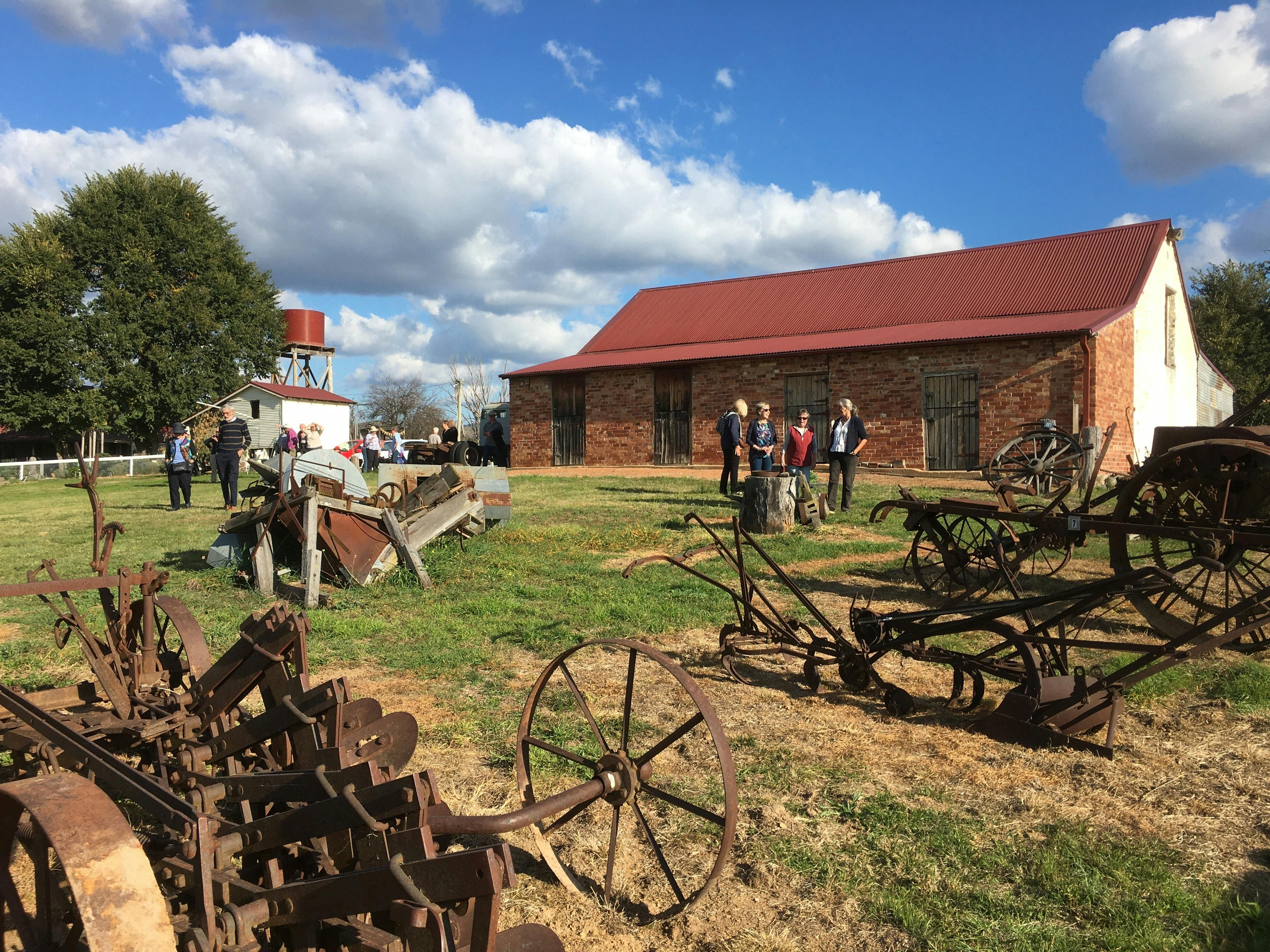 Rusted old plough outdoors in front of brick stables