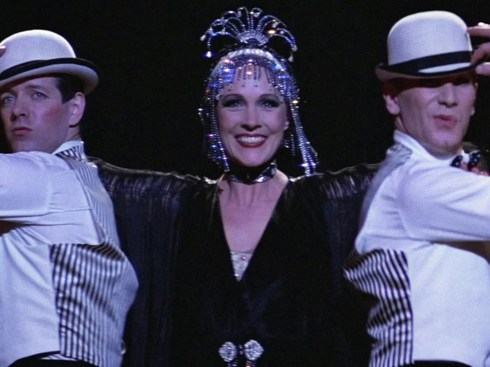 Woman performing with two men on either side wearing white hats