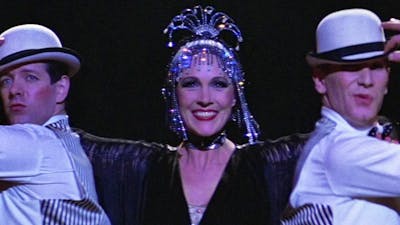 Woman performing with two men on either side wearing white hats