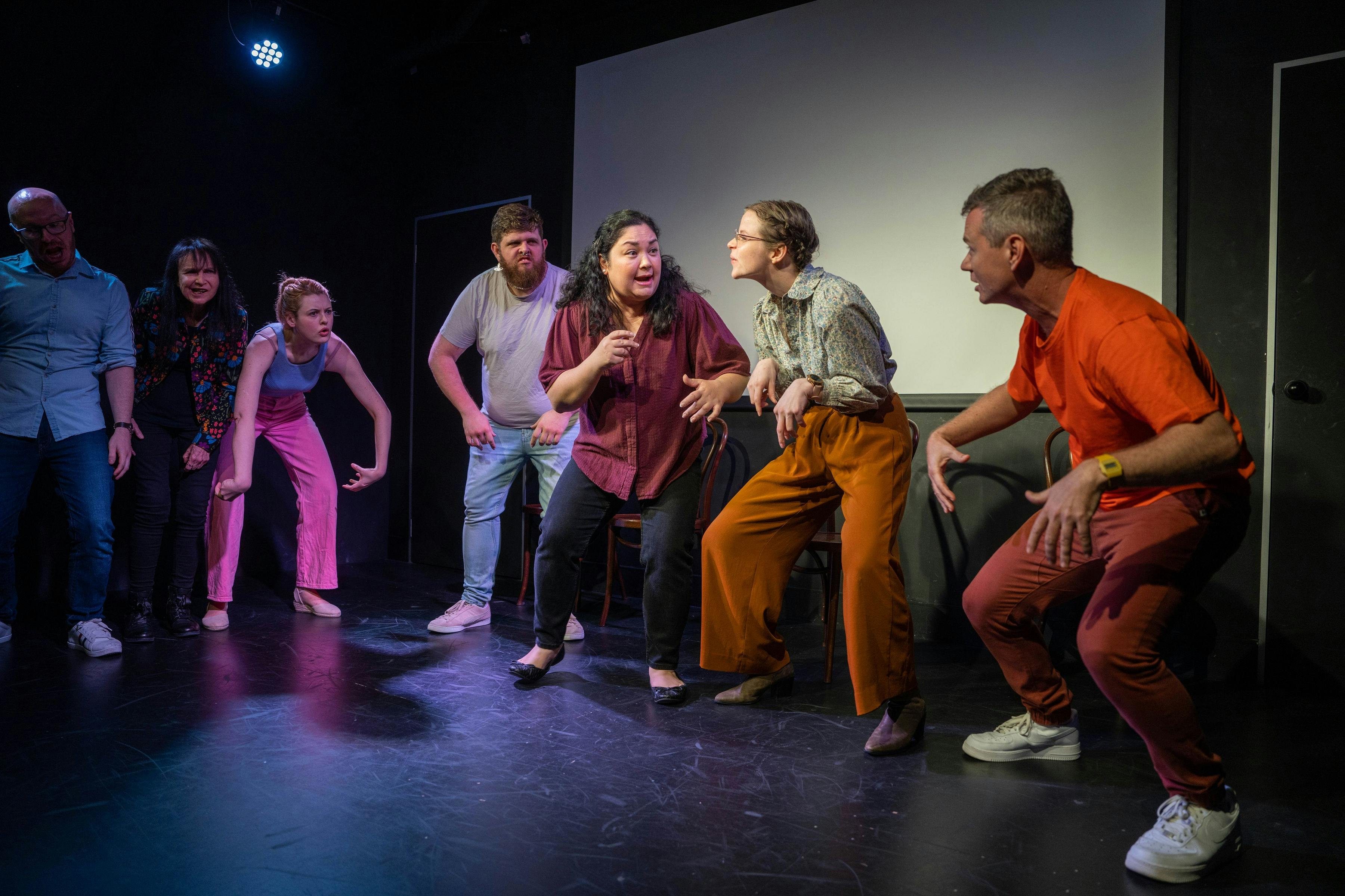 Five performers on stage hunched over like creatures, with the middle performer sharing their idea