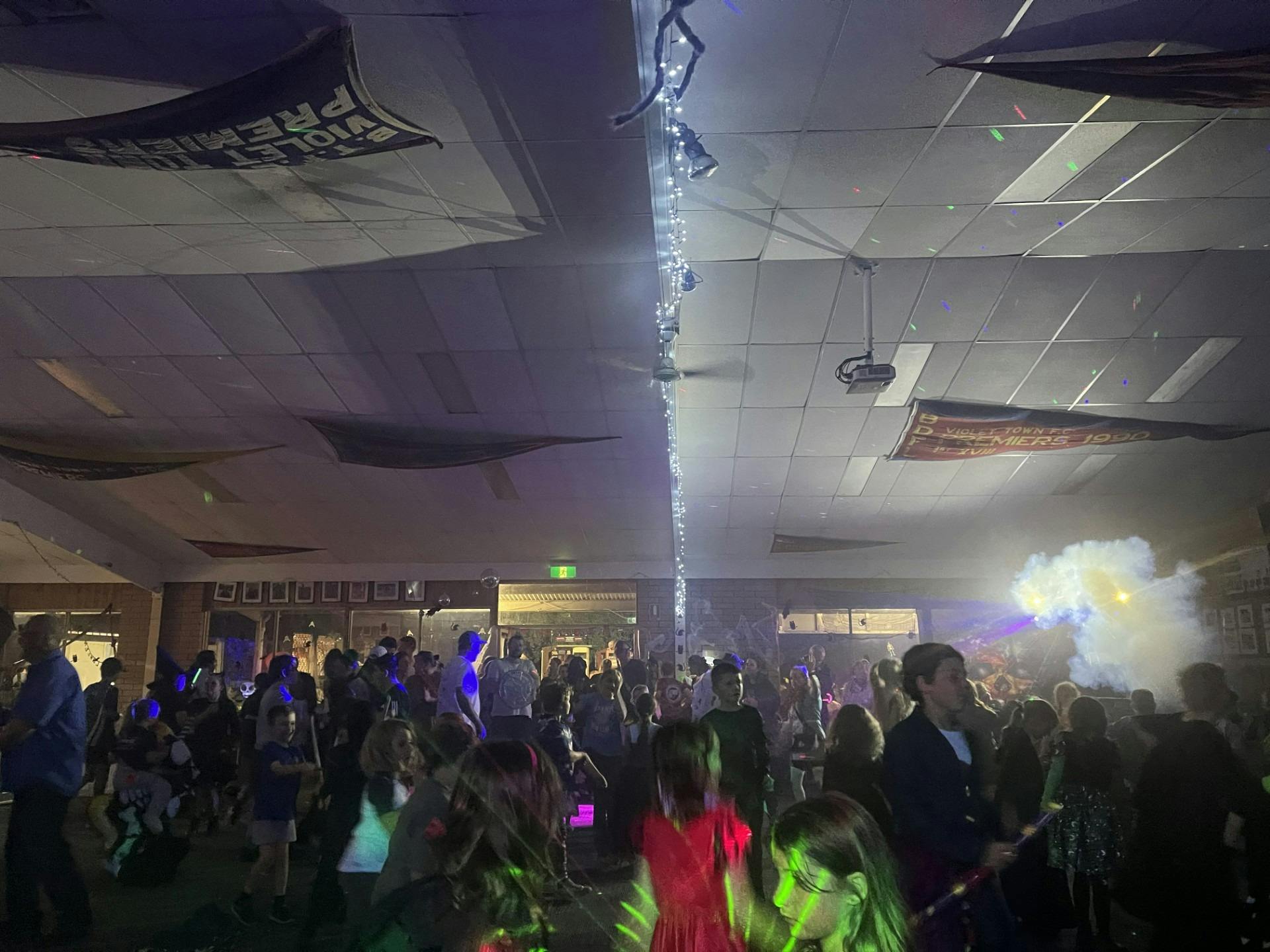 Children and adults in costume dancing inside clubrooms