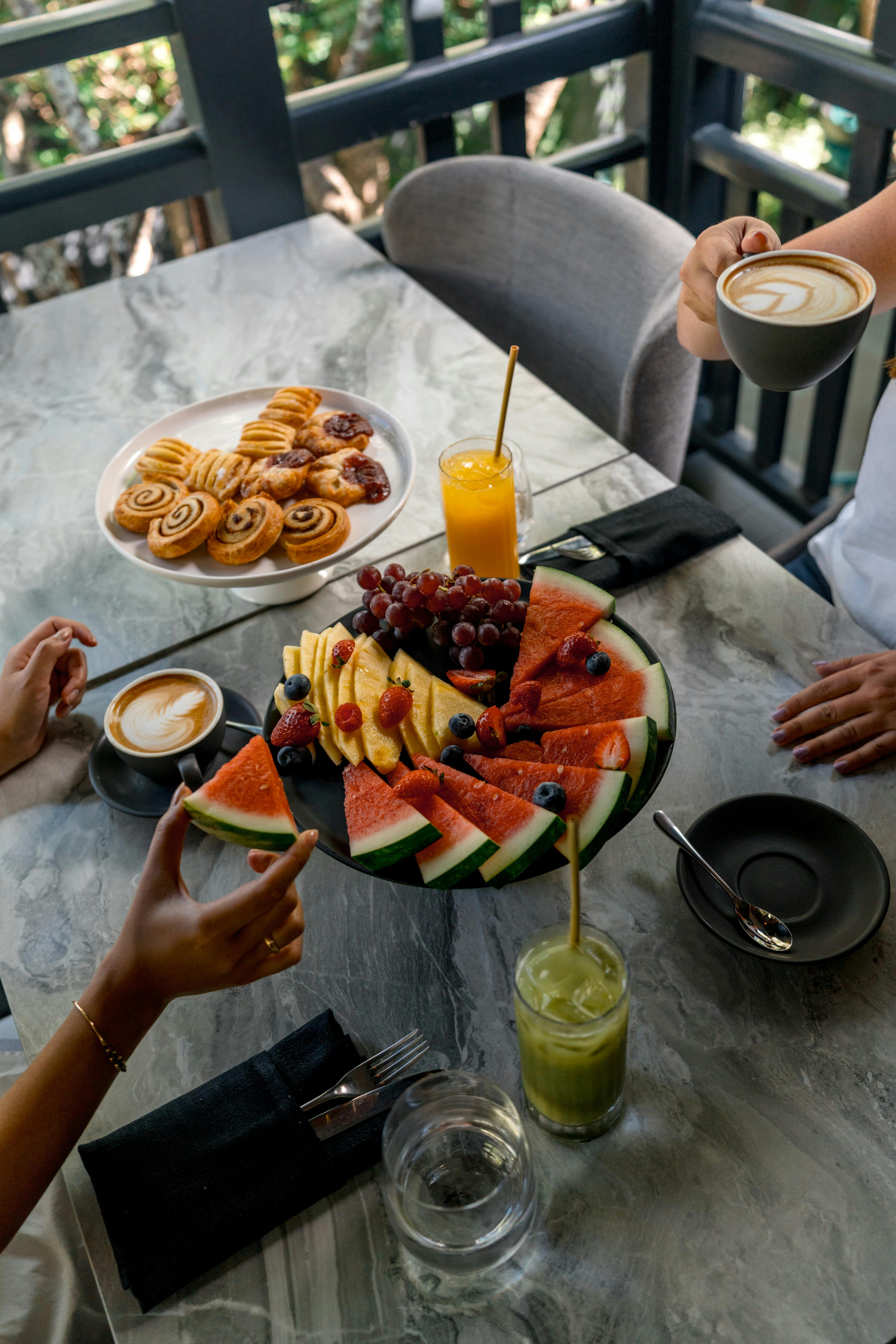 Hand grabbing fruit from large continental breakfast platter