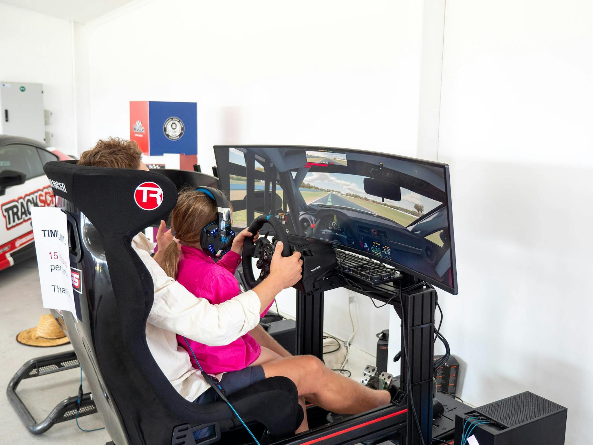 Parent and child sitting in a car racing sim