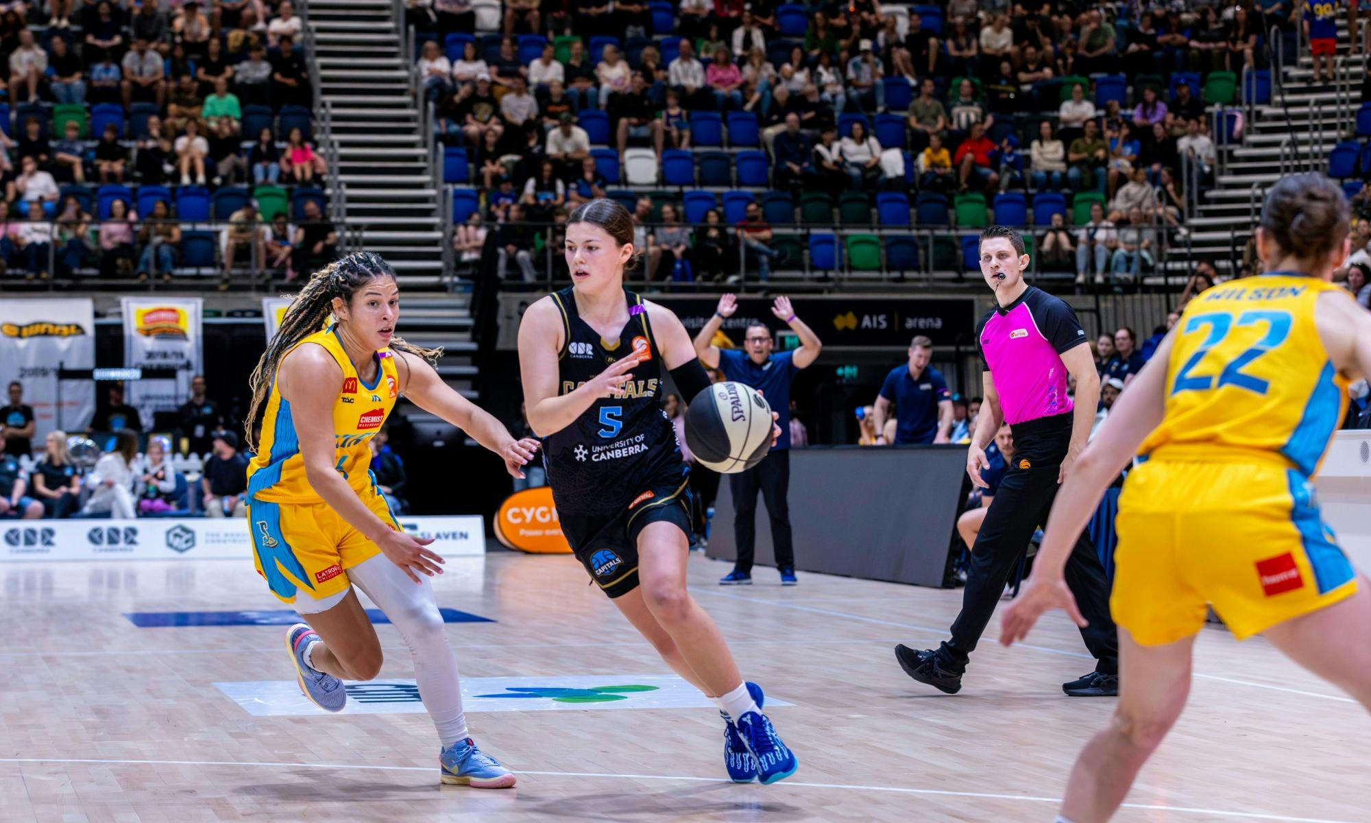 UC Capitals player driving to the basket for a layup during a WNBL game.