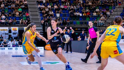 UC Capitals player driving to the basket for a layup during a WNBL game.