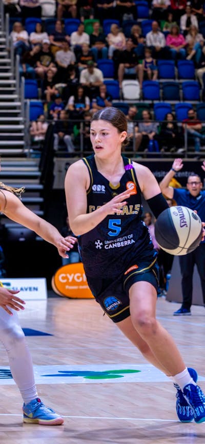 UC Capitals player driving to the basket for a layup during a WNBL game.